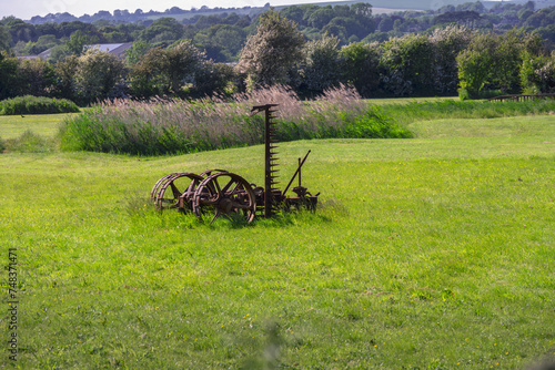 Old, rusty farm machinery in a field in spring, East Sussex, England