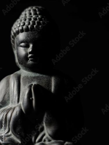 Betende Buddha Figur vor schwarzem Hintergrund