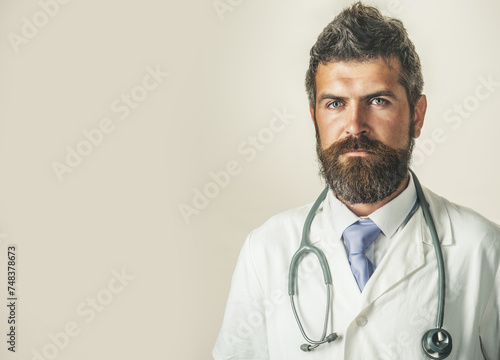 Clinic, treatment, medicine and healthcare - serious doctor in white medical coat with stethoscope. Ambulance service. Bearded physician in doctor uniform with stethoscope. Copy space for advertising.
