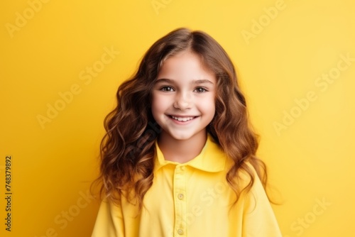 Portrait of a cute little girl with long curly hair over yellow background © Inigo