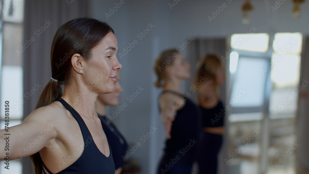 Woman coach performing training workout for female group. Media. Mentor explaining the technique of breathing with hands swings.