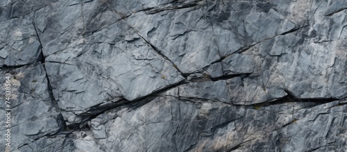 An elevated view of a grey, rugged granite stone surface forming a rock wall. The black and white image highlights the texture and shape of the rocks.