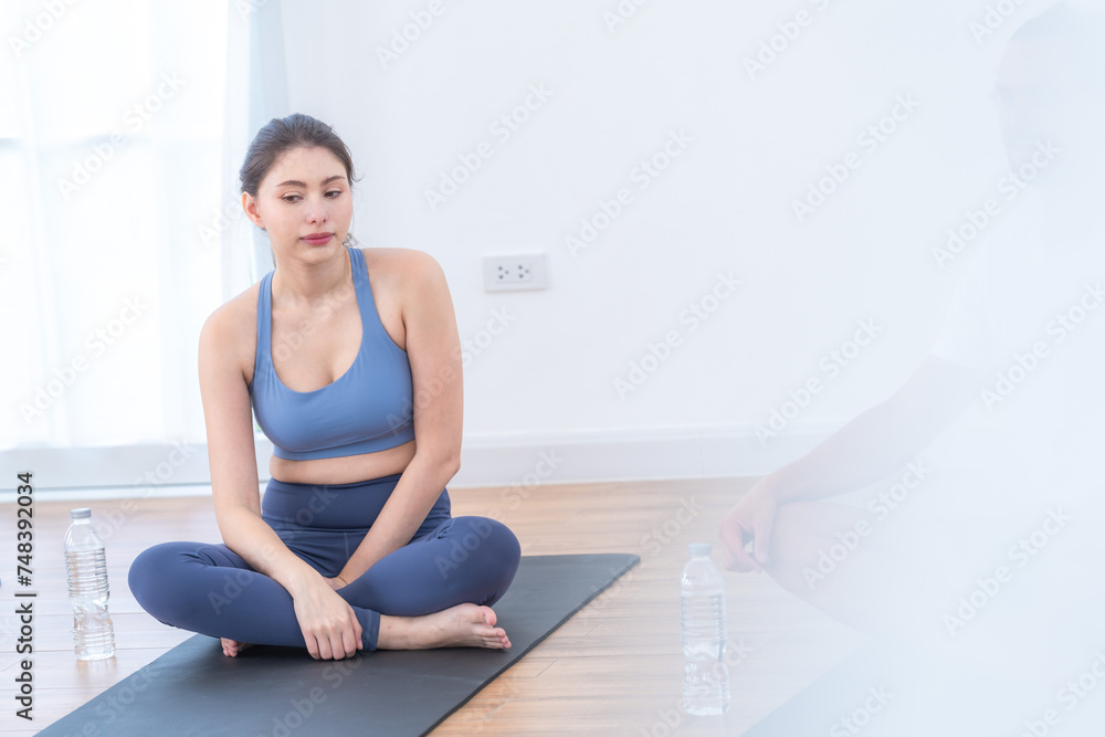 Fototapeta premium Two women confident training yoga. Athletic women in sportswear doing fitness stretching exercises at home in the living room. Sport and recreation concept. Yoga teacher is helping young woman.