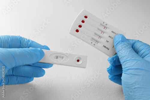 Doctor holding two disposable express tests at white table, closeup