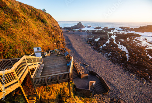 High angle view on Cobble Beach below Yaquina Head lighthouse with wooden stairs on the foreground in Newport, Oregon photo