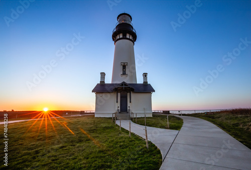 The Yaquina Head Lighthouse at Newport Oregon stands as a landmark. A beautiful Pacific sunset accents the outline of the Yaquina Head Lighthouse. photo