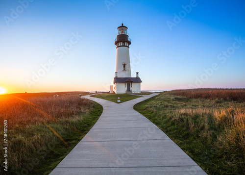 The Yaquina Head Lighthouse at Newport Oregon stands as a landmark. A beautiful Pacific sunset accents the outline of the Yaquina Head Lighthouse. photo