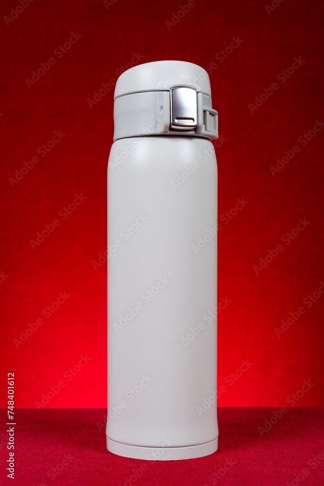 a white vacuum tumbler at vertical composition on red a white vacuum tumbler at vertical composition on red