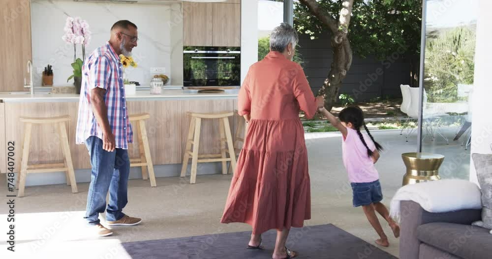 Biracial grandparents play with a young biracial girl indoors Biracial grandparents play with a young biracial girl indoors