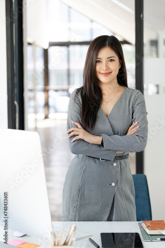 Portrait of young smiling woman looking at camera with crossed arms. © NAMPIX