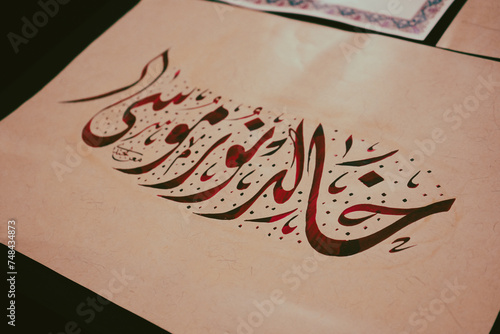 Writing in Arabic in Kufa script. Calligraphy. 
a drawing on a piece of paper. It includes text, handwriting, calligraphy, and ink, making it an art piece with a design and illustration. photo