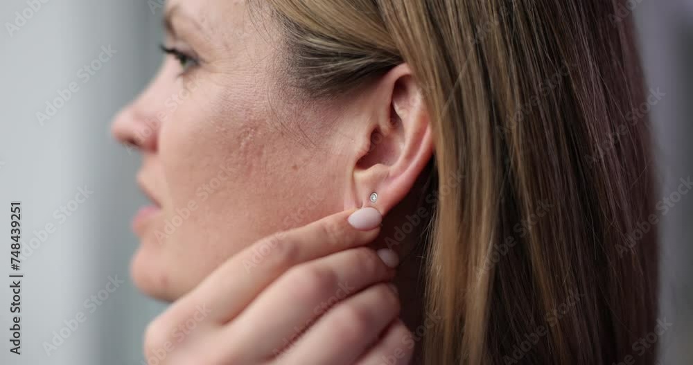 Beautiful woman puts long earring on ear Beautiful woman puts long earring on ear