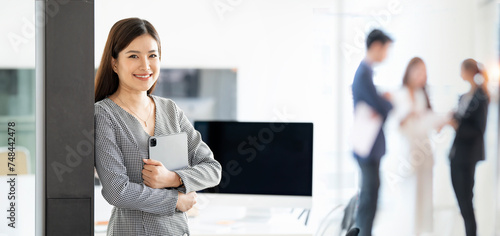 Modern business woman with tablet standing in office. Smiling to camera © NAMPIX