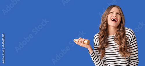 Beautiful young woman holding hair spray on blue background with space for text
