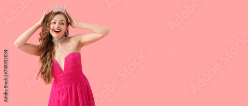 Young woman in crown and bright prom dress on pink background