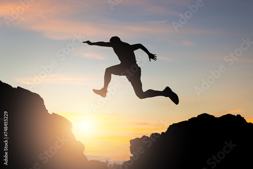 Silhouette of a person jumping in the sunset, a Sportsman jumping between mountain tops