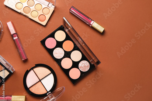 Beautiful palettes of eyeshadows and different decorative cosmetics on brown background
