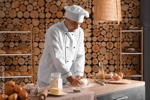 Young chef kneading dough o...
