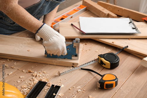 Female carpenter with construction stapler in workshop, closeup photo