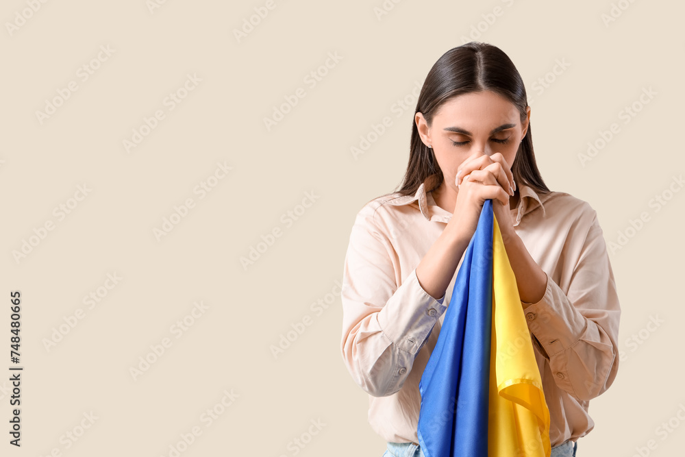 Beautiful woman with flag of Ukraine praying on light background Beautiful woman with flag of Ukraine praying on light background