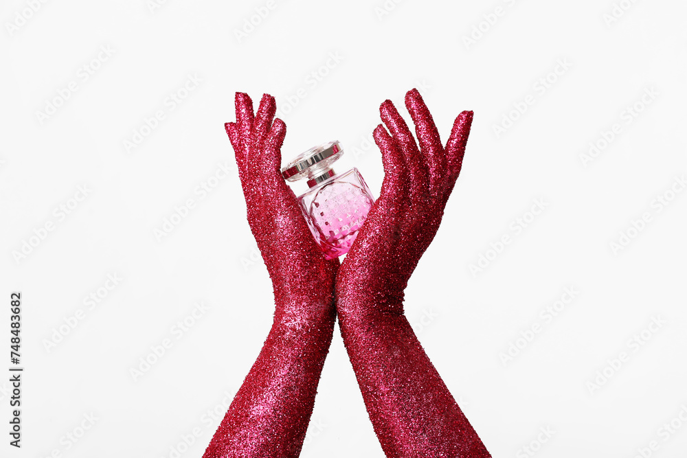 Painted female hands with bottle of perfume on white background, closeup Painted female hands with bottle of perfume on white background, closeup