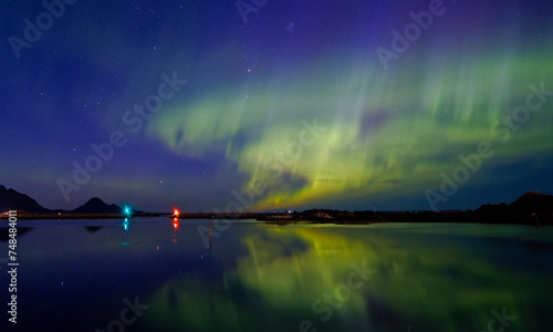 Obraz na plátně Aurora borealis/Northern Lights and its reflection on the bay separated from the sea by the breakwater with lighthouse on