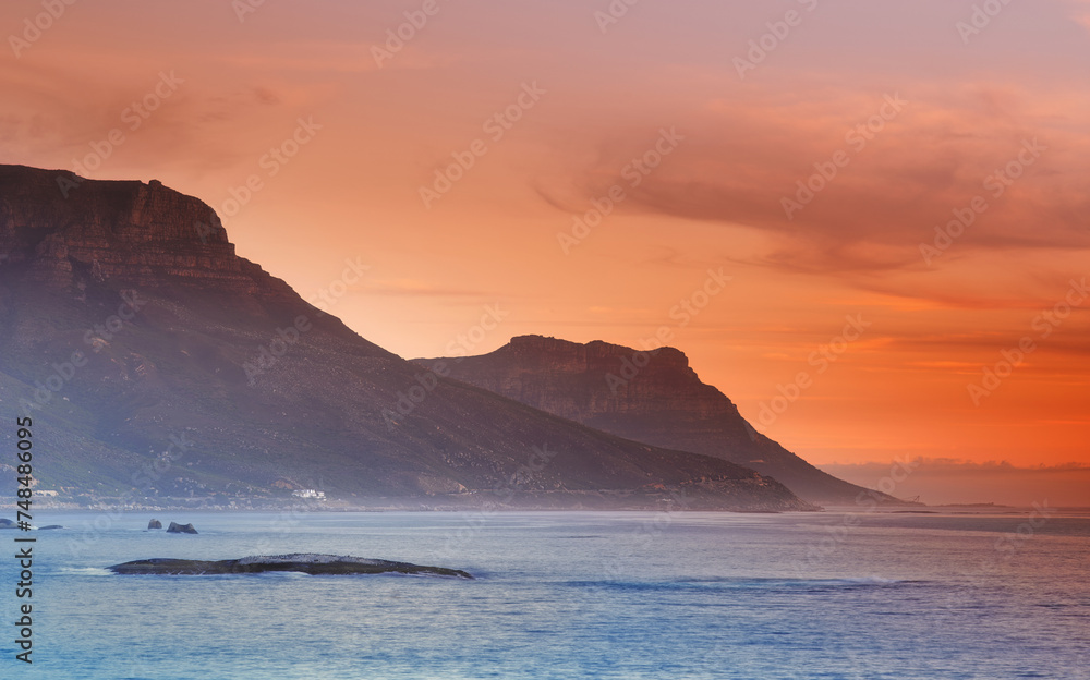 Ocean, sunset and mountains in nature or sustainable environment and travel destination for vacation. Landscape, sea or sunlight on water on beach, calm or seascape of camps bay for tourist adventure