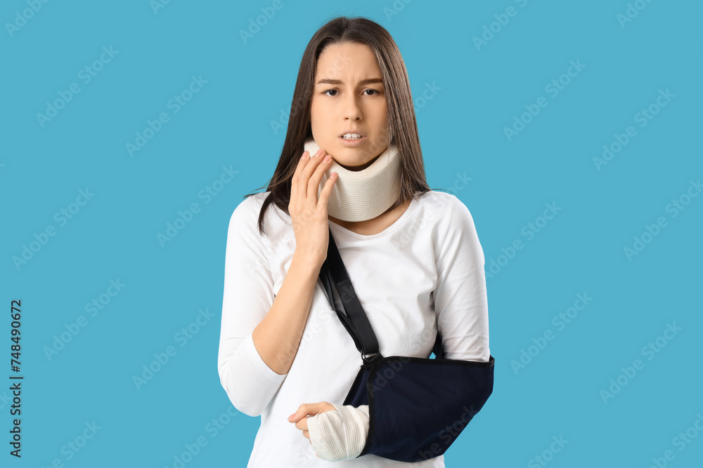 Injured young woman after accident with broken arm on blue background Injured young woman after accident with broken arm on blue background