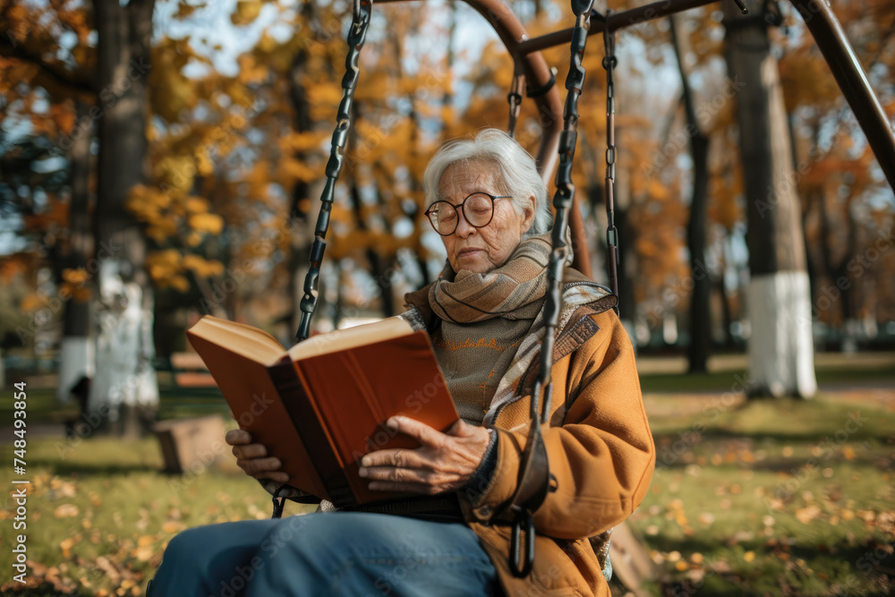 senior reading a book outside while sitting on a swing in the playground