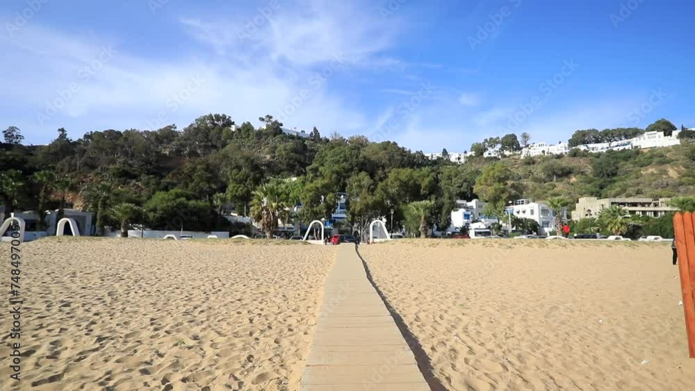 Wooden boardwalk leading to the sunny Sidi Bou Said beach in Tunisia, clear blue sky Wooden boardwalk leading to the sunny Sidi Bou Said beach in Tunisia, clear blue sky