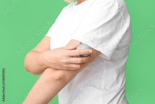 Woman with glucose sensor for measuring blood sugar level and applicator on green background  closeup. Diabetes concept