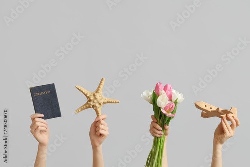 Female hands with wooden toy plane, passport, starfish and flowers for International Women's Day on grey background © Pixel-Shot