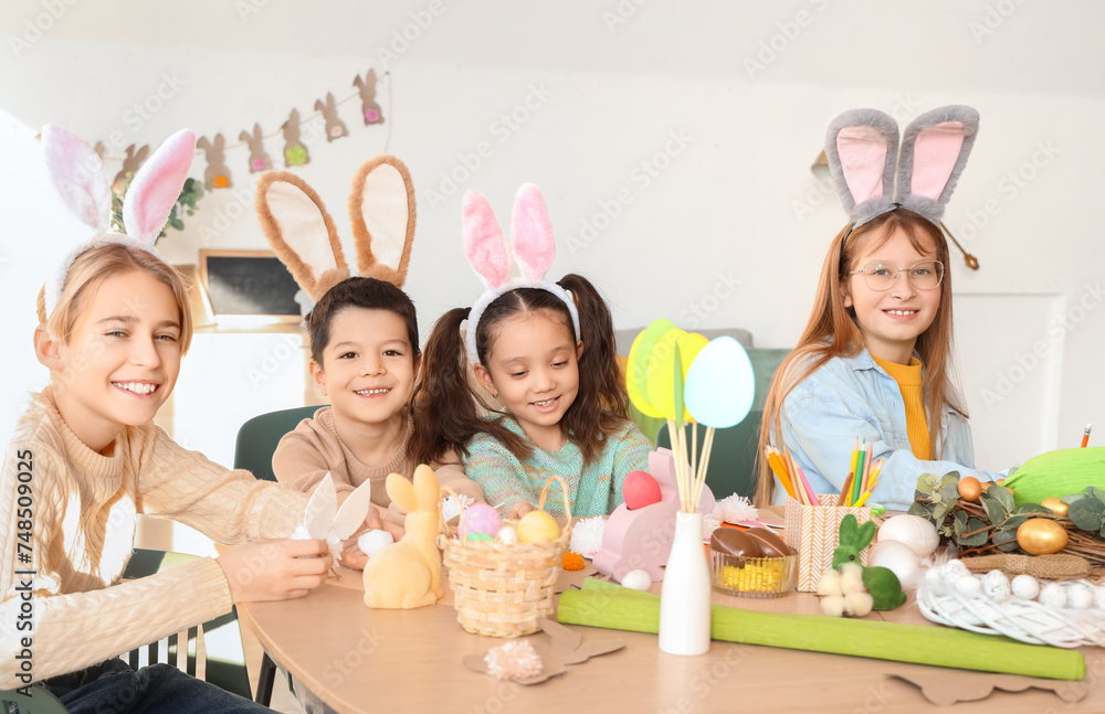 Little children in bunny ears making Easter crafts at table Little children in bunny ears making Easter crafts at table