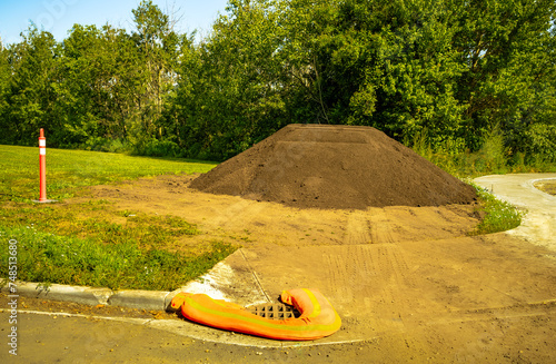 Photos A pile of topsoil on the edge of park open space field with filter sock on front