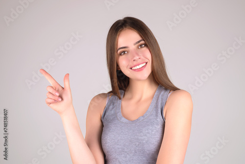 The Copy space point. Young woman pointing copy space. Studio portrait of Girl pointing away on isolated gray background. Pretty woman gesturing with fingers, showing away.