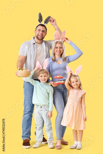 Happy family in bunny ears with Easter eggs on yellow background © Pixel-Shot