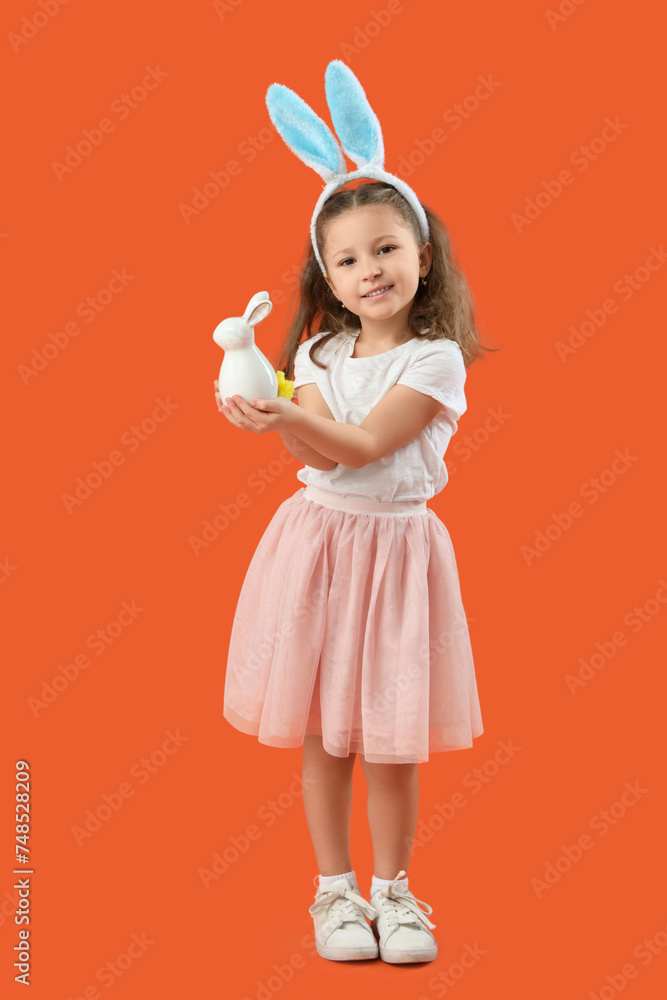 Cute little girl in bunny ears with rabbit on orange background. Easter celebration Cute little girl in bunny ears with rabbit on orange background. Easter celebration
