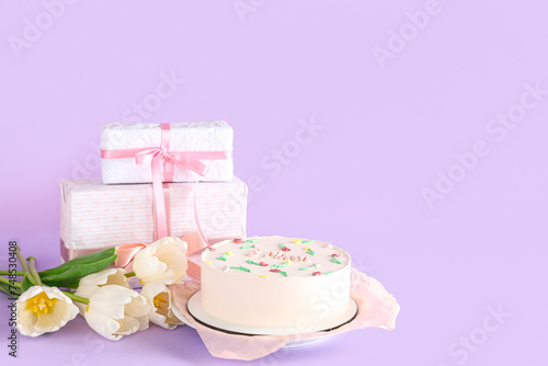 Sweet bento cake with beautiful tulips and gift boxes on lilac background. International Women s Day