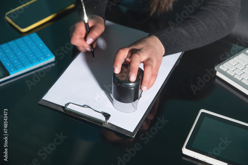 Business woman using stamp on document.