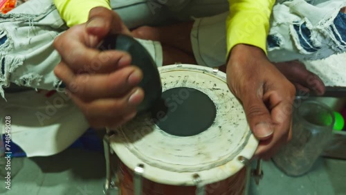 Closeup of hands playing a traditional drum capturing the essence of cultural music man repairing drum at musical workshop photo