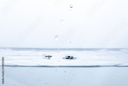 A droplet of water reflects off clear water, creating a mesmerizing splash. Ideal for showcasing water dynamics or the purity of liquid elements.