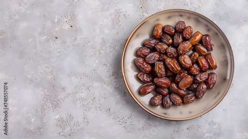Top view shot of a dish filled with dates on a concrete background