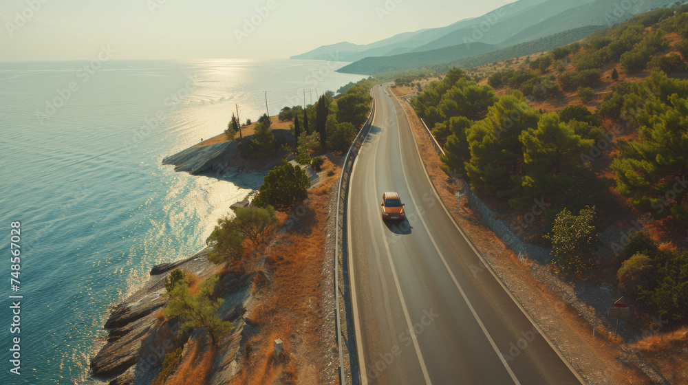 Obraz premium Car driving along a scenic coastal road at sunset.