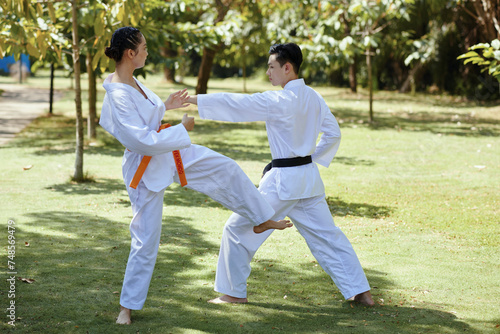 Girl with orange belt defending when fighting with black belt taekwondo athlete