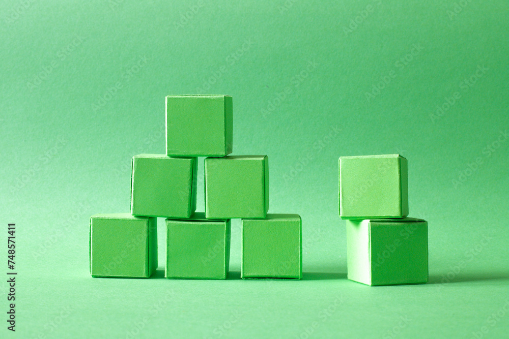 Green Cubes Organized in a Pyramid Formation on Uniform Teal Green Background Representing Eco-Friendly Development Green Cubes Organized in a Pyramid Formation on Uniform Teal Green Background Representing Eco-Friendly Development