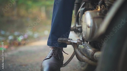 Closeup shot of a man trying to kick start an old motorbike photo