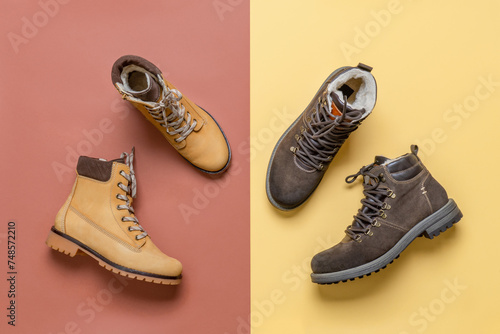 Two pairs of yellow and brown men's and women's winter suede leather stylish boots on color background. Casual trendy footwear, shopping, sale, shoes fashion concept. Flat lay, top view
