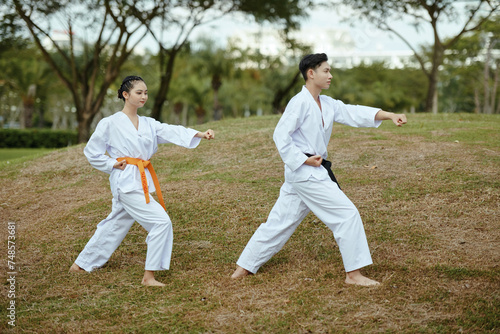 Taekwondo sportsmen in uniform working out outdoors