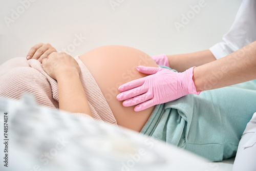 Cuadro en lienzo Gynecologist-obstetrician in medical gloves examining belly of pregnant woman