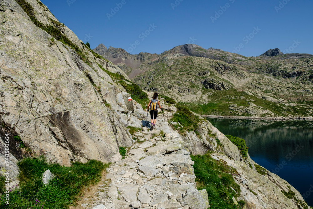hiker on Bachimaña reservoir, Ibones azules and Bachimaña alto route, Huesca province, Spain
